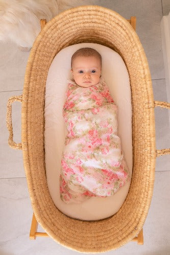 baby in basket swaddled in peony floral muslin