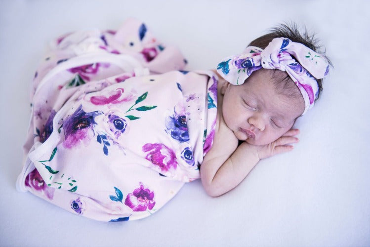 newborn in floral kiss jersey swaddle and topknot
