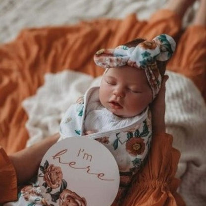 mother holding baby in Florence swaddle topknot and milestone card