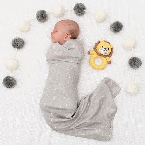 baby in grey jersey swaddle with knitted lion rattle