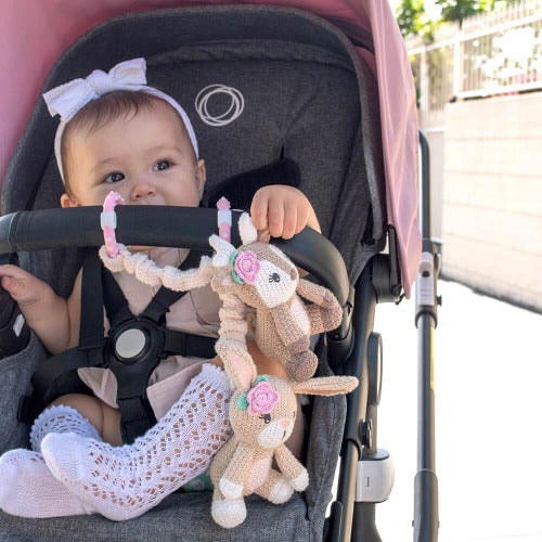 baby in stroller with fawn and bunny pram toy