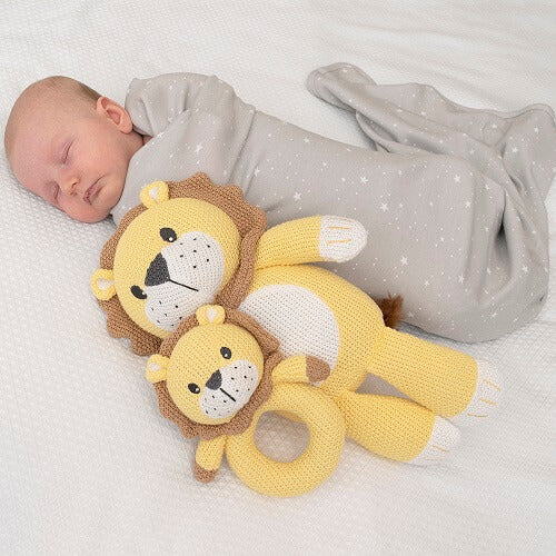 baby asleep in swaddle with lion toy and rattle