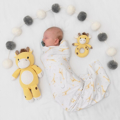 baby in swaddle with giraffe ring rattle and toy
